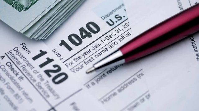 Tax Form 1040, 1120, and dollar bills, close up.
