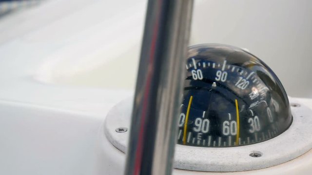 Closeup on sailing boats compass looking through steering wheel turning round. Filmed in slow motion hd.