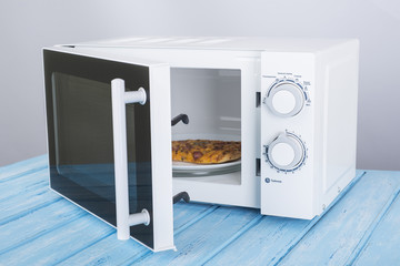 A new white microwave oven, on a blue wooden surface for heating food