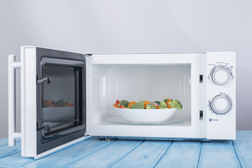 A new white microwave oven, on a blue wooden surface for heating food