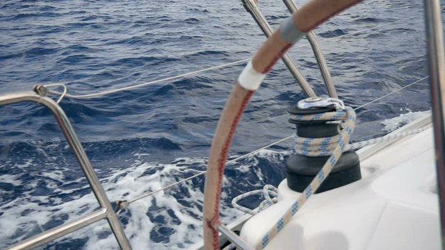 Closeup on left sailing boats winch looking through steering wheel turning round. Filmed on moving sailing boat in slow motion hd.