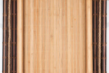 Bamboo mat with curled edges and rope, on white background. Space for text.
