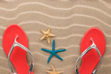 Beach fashion, pink flip-flops and starfish standing in the sand beach.