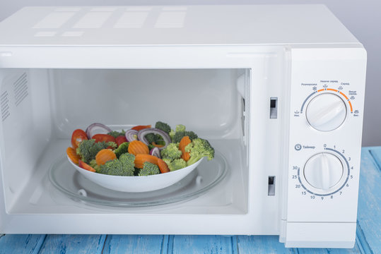 A new white microwave oven, on a blue wooden surface for heating food
