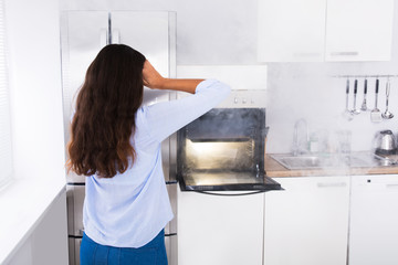 Shocked Woman Looking At Smoke Coming From Oven