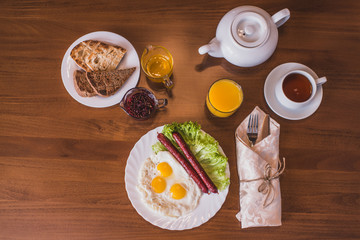 Breakfast on the table in the hotel room. Breakfast served with tea, fried eggs, orange juice, toasts. Omelet. Balanced diet.  napitokнапитокbabkikhliebpanirovat andбабкипанировать andхлебzavtrakzavtr