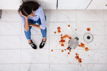 Woman Sitting On Kitchen Floor With Spilled Food