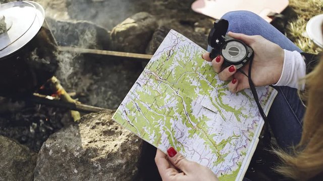 Hands of a woman holding a map and a compass