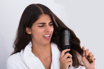 Woman In Bathrobe Brushing Her Curly Hair
