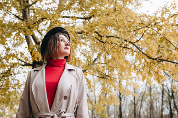 woman in trench coat at autumn park