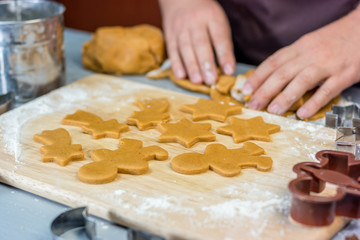 Woman makes christmas gingerbread cookies. Dough and metal cutters on wooden table, horizontal
