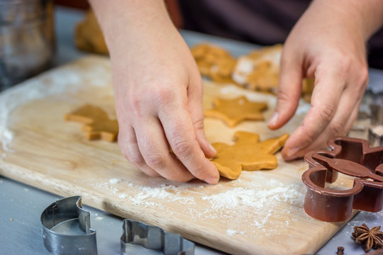 Woman makes christmas gingerbread cookies. Dough and metal cutters on wooden table, horizontal