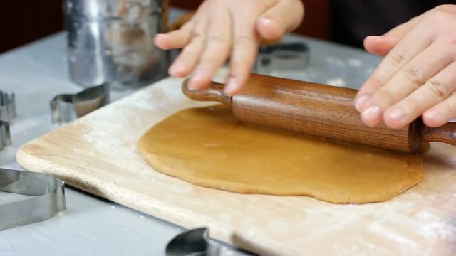 Woman roll out the dough with a wooden rolling pen. Making christmas gingerbread cookies