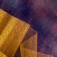 Gold thread and gliters on the fabric texture. Textile roll with waves and wrinkles on the dark cosmic stone surface. Concept Design background. Space for text, selective focus. Square card