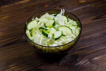 Spring vegan salad with cabbage and cucumber on wooden table