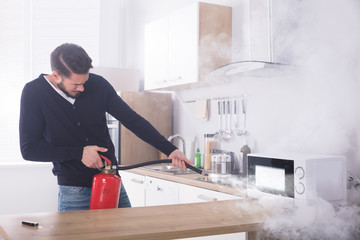 Man Spraying Fire Extinguisher On Microwave Oven
