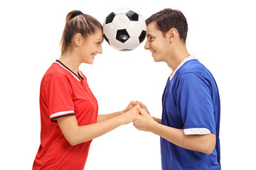 Female footballer and a male footballer holding a football between their heads © Ljupco Smokovski