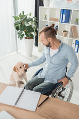 man on wheelchair petting his dog