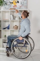 man on wheelchair trying to reach for book