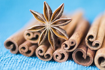 Obraz na płótnie Canvas Spices: star anise and cinnamon sticks on a blue background. Close-up. Blur