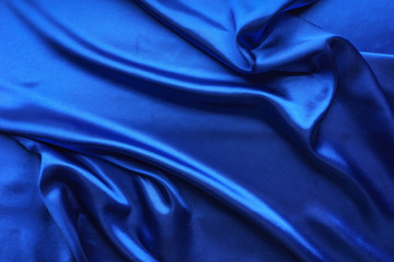 Blue satin, silky fabric, wave, draperies. Beautiful textile backdrop. Close-up. Top view 