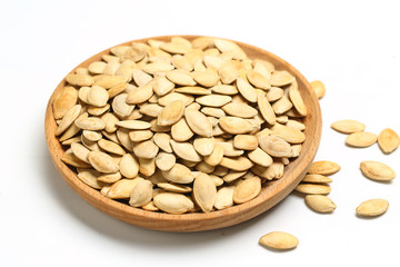 pumpkin seeds in wooden plate isolated on white background