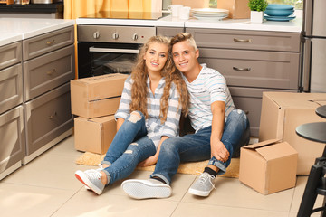 Fototapeta na wymiar Young couple with moving boxes on floor in kitchen