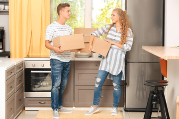 Fototapeta na wymiar Young couple with moving boxes in kitchen