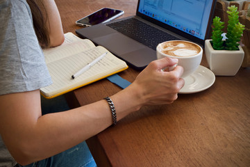 Fototapeta na wymiar Woman drinking coffee and using laptop 