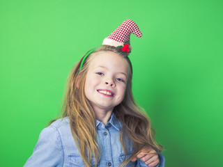 young girl with christmas decoration on head in front of green background