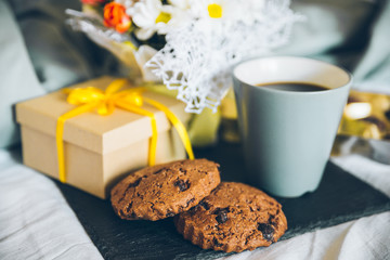 cookies, chocolate, flowers gift box and phone on the bed