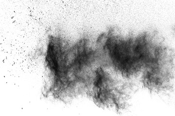 Black powder explosion. The particles of charcoal splatter on white background. Closeup of black dust particles splash isolated on  background.