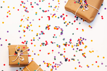 Gift boxes wrapped in kraft paper with confetti on white background. Top view
