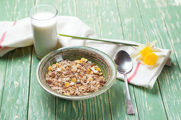 Bowl of oat flakes and glass of milk, on wooden background. Selective focus.