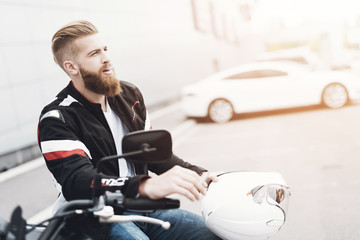 Fototapeta na wymiar A young guy with a beard sits on his electric motorcycle.