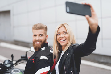 Young guy and girl doing selfie, sitting on a modern electric motorcycle.