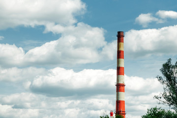 Industrial chimney against the sky with clouds