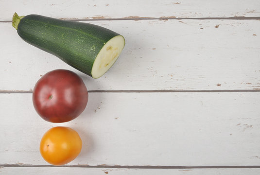 Tomaten und Zuchhini auf verwittertem Holz
