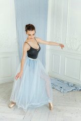 Young classical Ballet dancer side view. Beautiful graceful ballerine practice ballet positions in tutu skirt near large mirror in white light hall. Ballet class training, high-key soft toning