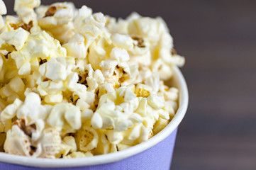 Popcorn in a bucket bucket is a top view on a dark wooden background. Macro shot from above.