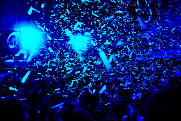 Confetti fired in the air during a in a disco. Hundreds of hands to the sky. Blu tone/background with high contrast