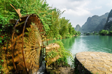 Moving water wheel (noria) on the Yulong River, Guilin, China - obrazy, fototapety, plakaty
