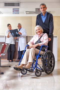 Doctor with elderly female patient on wheelchair at hospital