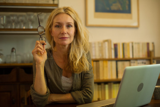 Mature woman sitting at home with laptop computer, portrait