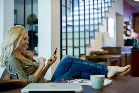 Woman relaxing at home with smartphone