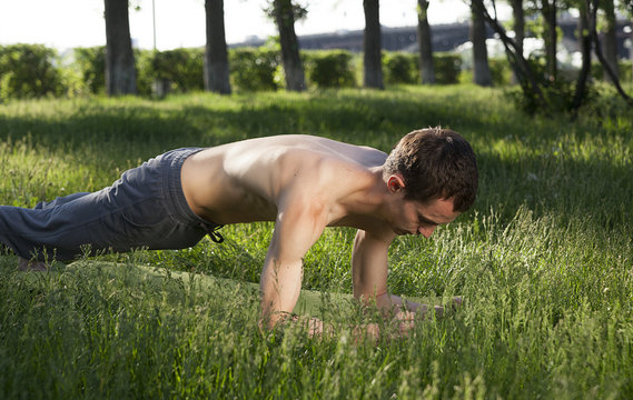 young man is engaged in gymnastics in the park,  bar,  power exercise
