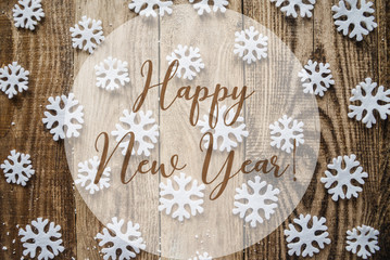 the inscription happy new year  on wooden background with white snowflakes