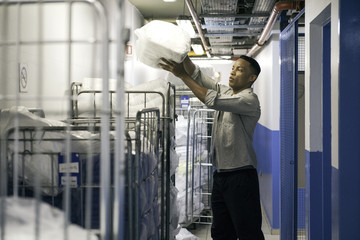 Man loading laundered bath towels into cart