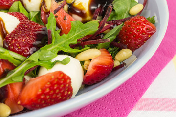 summer salad bowl with strawberries, field salad, beetroot, arugula, mozzarella and pine nuts with balsamic vinegar