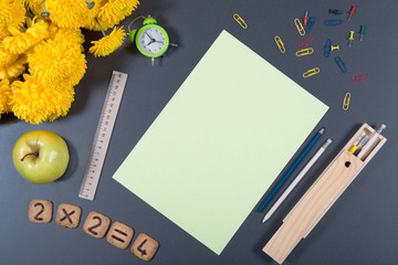 Colorful school background. Desk surface with clock, apple, cookies with numbers, ruler, paper sheet; clips, drawing pins, etc. Healthy snack.